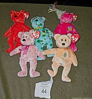 Five TY Beanie Baby bears arranged on green carpet, showing color variations and tag hearts.