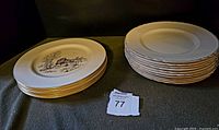 Two stacks of plates; left stack of 5 Lenox plates with scene and gold rim, right stack of 10 Myott plates with gold rim