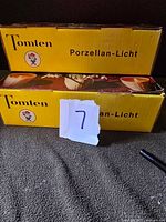 Yellow Tomten boxes labeled 'Porzellan-Licht' with logo and product name visible