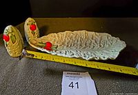 Photo of ceramic salad plate, shaped like a textured leaf with two red tomatoes on one side, alongside matching tomato salt and pepper shakers. Measuring tape shows plate length about 9 inches.