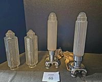 Two ornate metal lamps each with a frosted ribbed glass pillar shade, placed alongside two extra clear ribbed glass shades. Note visible power cords on lamps, showing bases and shades included.