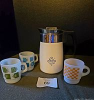Full view of Corning Ware stove top percolator with three Fireking mugs - two blue starburst and one orange checkerboard.