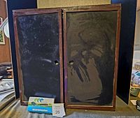Closed wooden case with double-sided chalkboards on doors, showing the outer side of the doors.