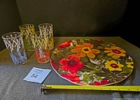 Photo showing the round floral serving tray with 4 glass tumblers, measuring tape indicating size, and auction lot number.