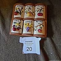 Front view of assembled vintage ceramic spice rack with 6 labeled ceramic jars (Ginger, Clove, Pepper, Salt, Spice, Nutmeg) and wooden rack base.