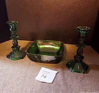 Green glass console bowl and two green glass candlesticks arranged together on a flat surface with seller's lot tag in view.