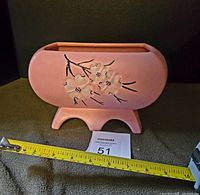 Front and side views of pink McCoy pottery planter with white dogwood flowers. Measuring tape shows approximate width of 8.5 inches.