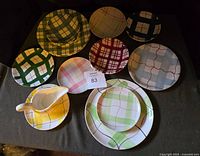 Top view of the assorted plaid patterned plates, saucers, and gravy boat showing variety of colors, primarily yellow, green, red, and blue patterns.