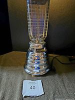 Front view of the vintage Osterizer blender with glass jar and chrome base showing the logo and toggle switch.