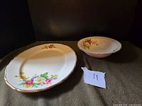 Wide view of the oval platter and matching bowl showing overall condition and floral decoration.