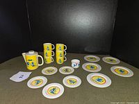 Full view of the set including teapot, stacked cups, plates, and small white cup with Smurf design.