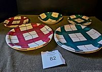 Photo of all 8 plates and 1 bowl displayed, showing the red and teal check patterns on white ironstone.