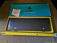 Photo showing the tie holder inside the open box with measuring tape indicating approximately 16 inches in length.