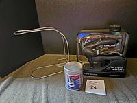 Photo showing the metal wine bottle holder stand, Rabbit corkscrew opener with foil remover, and extra corkscrew in front of a dark background on a fabric surface.