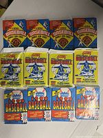 12 unopened vintage 1990 MLB baseball card packs including Bowman, Fleer, and Score brands laid out on flat surface.