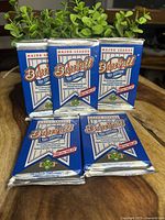 Five unopened 1991 Upper Deck Baseball card packs stacked showing the front of the packs, blue and white with Major League Baseball logo and markings.