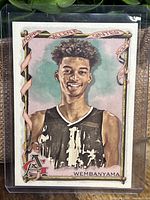 Front-side of the 2023 Allen & Ginter Victor Wembanyama rookie card showing his portrait illustration and design elements.