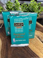 Four foil-sealed 1991 SkyBox Series II Inaugural Edition NBA trading card packs in teal packaging, stacked and arranged with some resting upright and some leaning.