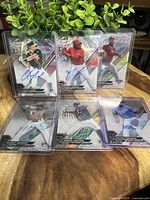 Photo of all six autographed Topps Tek rookie acetate cards arranged standing on a table, showing full card fronts with signature and player image.