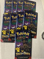 Front view of nine sealed Pokémon Trick or Trade card packs, showing colorful packaging featuring Gengar, Pikachu, Trevenant, and other Pokémon characters.