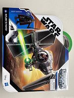 Front view of Outland TIE Fighter box showcasing the vehicle firing a green laser in space