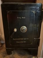 Front view of black safe showing door, gold lettering, lever handle and combination dial