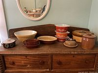 Full view of all kitchenware items arranged on wood surface including bowls, covered dishes, and jars.