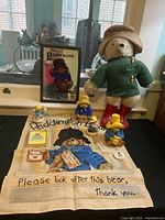 Photo showing the entire Paddington Bear collection including plush bear, figurines, decorative cloth, framed art, and book