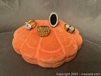 Four 18K electroplated rings displayed on an orange shell-shaped cushion; showing front view of all rings.