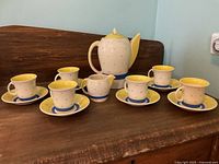 Full set display showing teapot, six cups and saucers arranged on wood surface.