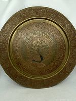 Front view of 12-inch brass etched wall plate featuring a colorful peacock design and floral etched rim.