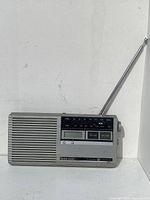 Front view of the 1980s General Electric Bathmate AM FM Portable Radio showing speaker grille, AM/FM frequency scale, digital display, control buttons, and telescopic antenna.