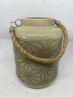 Front side view of the ceramic beige patio lantern with dotted geometric star pattern and rope handle.
