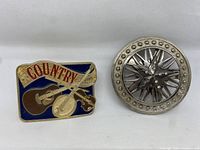 Country themed belt buckle showing guitar, violin, banjo and red 'COUNTRY' lettering on blue background