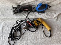 Overall view of the three tools: black Craftsman rotary tool, blue palm sander, yellow corded drill