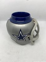 Front and side perspective of the silver helmet-shaped mug with blue interior and Dallas Cowboys star logo.