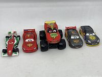 Five Disney/Pixar Cars die-cast toy vehicles lined in a row on white background
