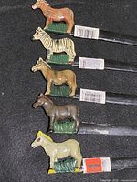 Five handpainted animal figure letter openers arranged lengthwise.