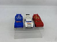 Set of three Hot Wheels Track Stars toy cars shown from front and slightly above, arranged in a row on a clear display stand.