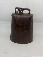 Front view of large vintage authentic cow bell with handle and spring clapper mechanism.