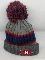 Front and top view of Montreal Canadiens knit tuque hat showing pom-pom and color scheme.