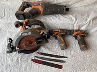 Overview of the tools laid on a cloth showing the saws, drill drivers, and blades