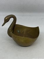 Front and side view of vintage brass swan bowl showing patina and oxidation spots