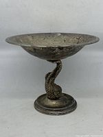 Front view of vintage silver plated bowl with visible fish design on stem and patinated surface