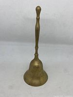 Front view of the vintage brass handbell showing full length and shape