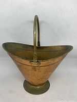 Front view of vintage brass fireplace bucket showing conical shape, flared rim, and handle.