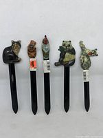 Front view of 5 hand painted vintage animal letter openers, showing details of cat, dog, rooster, panda, and wolf/dog figures.