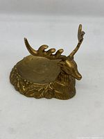Side view of solid brass deer head piece showing detailed antlers and textured base