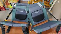 Front view of two L.L.Bean folding seats, showing padded backs and seats in gray and green fabric with black seat sections and logos.