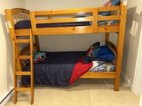 Frontal angle view of assembled wooden twin bunk beds with bedding.
